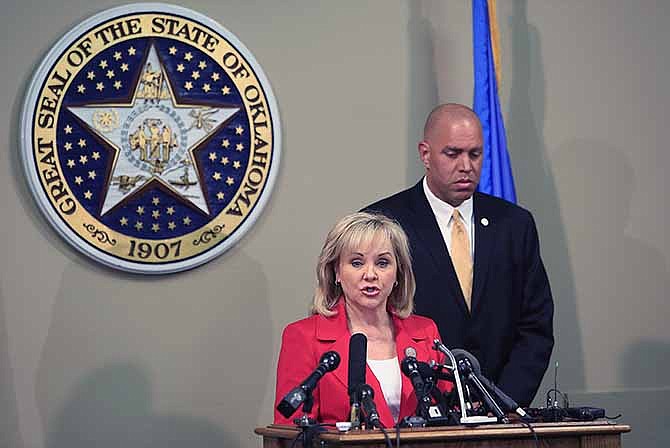 In this April 30, 2014 file photo, Oklahoma Gov. Mary Fallin, front, issues a statement to the media on the Execution of Clayton Lockett as Oklahoma Secretary of Safety and Security Michael C. Thompson, back, listens from the Oklahoma State Capitol in Oklahoma City. The botched execution of Lockett, and the gruesome details of him writhing and moaning before dying of a heart attack, has outraged death penalty opponents, raised the potential of more court challenges and received international attention.