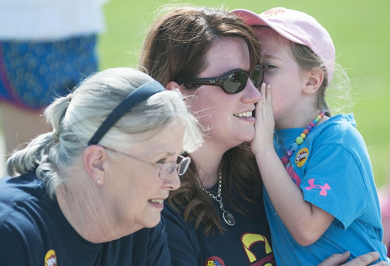 Ava Santhuff (right), 5, of Fulton whispers in her mother's ear as they along with Ava's grandmother, Martha Wayne, judge the costume contest Sunday at the Super Sam Family Fun Run.