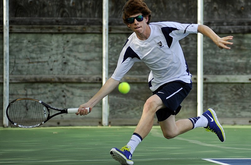 Ryan Pollock of Helias stretches for a forehand as he and teammate T.J. Hagenhoff take on a School of the Osage team in the No. 3 doubles match during Monday's dual at Washington Park.