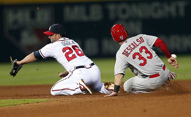 St. Louis Cardinals shortstop Daniel Descalso (33) steals second base as the ball gets past Atlanta Braves second baseman Dan Uggla (26) in the seventh inning of a baseball game, Tuesday, May 6, 2014, in Atlanta.