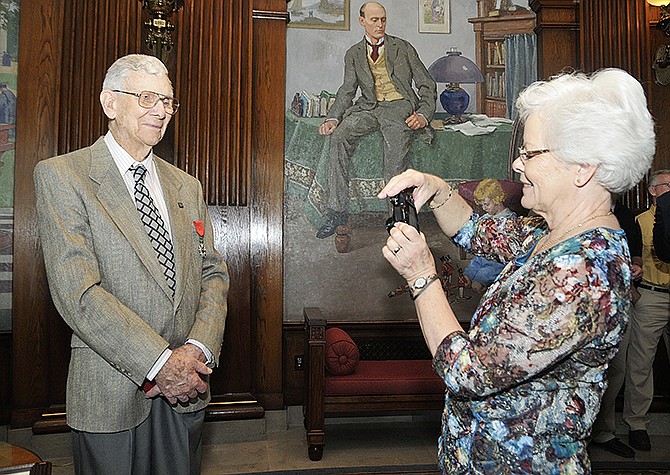 Carol Pendleton, oldest daughter of Ray Herigon, photographs her father with the medal he just received. The World War II veteran was presented the French Legion of Honor medal by Jim MauzÃ©, the honorary consul of France in St. Louis. 