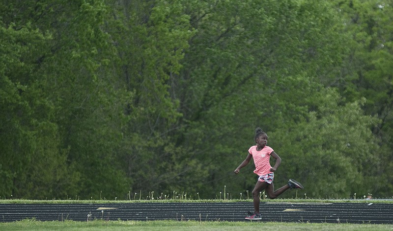 Quiara Walton, third grade student at McIntire Elementary, looks behind her to check the distance between her and the next runner as she runs the 400-meter dash Thursday during a field day for third graders in the district. Walton came in first in the race at the Fulton High School track, which included third grade girls from McIntire, Bush and Bartley elementary schools. She also beat all the other third grade girls to place first in the 100-meter dash.