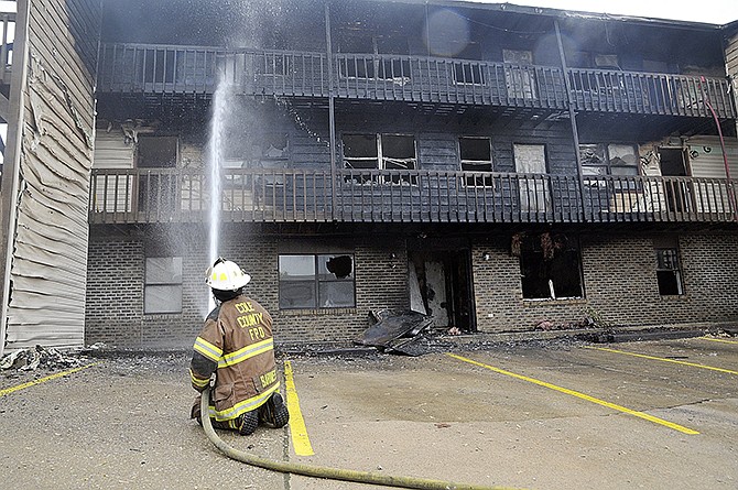 Asst. Chief Steve Barnes of the Cole County Fire Protection District continues to spray water on the building's exterior to prevent further flare-ups while fellow firefighters were inside individual apartments trying to douse flames.