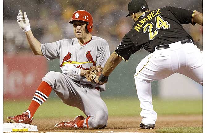 St. Louis Cardinals' Peter Bourjos, left, slides into third ahead if the tag by Pittsburgh Pirates third baseman Pedro Alvarez (24) with a triple in the fourth inning of a baseball game in the rain on Friday, May 9, 2014, in Pittsburgh. 