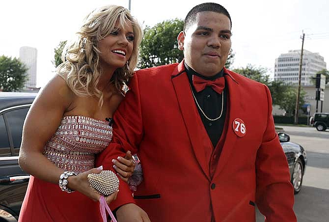 High school student Michael Ramirez, right, and Houston Texans cheerleader Caitlyn pose for pictures outside a restaurant before attending the prom Saturday, May 10, 2014, in Houston. Ramirez sent Caitlyn a Twitter message saying "If I get 10,000 retweets will you go to prom with me (insert smiley face.) you will get asked in a cute way!" He did and so she said yes.