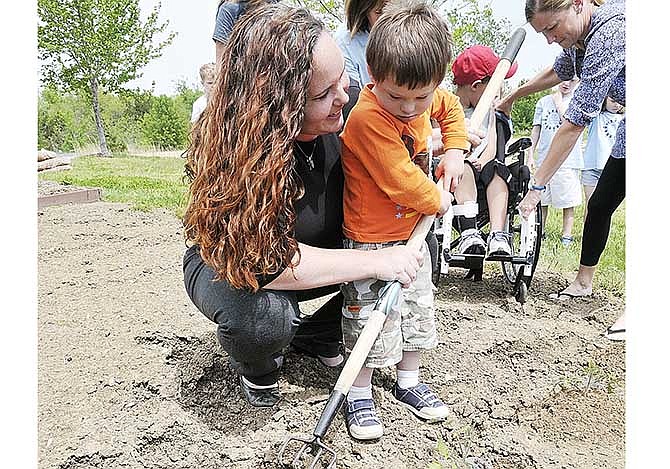 April Drewel shows Reece Gjesvold how to use a four-pronged hoe to break up the soil prior to planting. In honor of her son, Alex, who attended The Special Learning Center, Drewel volunteers numerous hours each summer to prepare, plant and tend the small but productive garden behind the school.