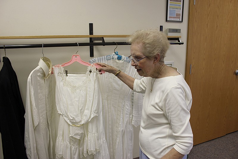 Callaway County Family and Community Education (FCE) Council Vice President Umbra Duffy inspects hemming on her aunt in-law's dress during the FCE's annual May Tea Monday at the Callaway County Extension Center. Behind her, on a blue hanger, is her mother's wedding dress from when she was married in 1909.
