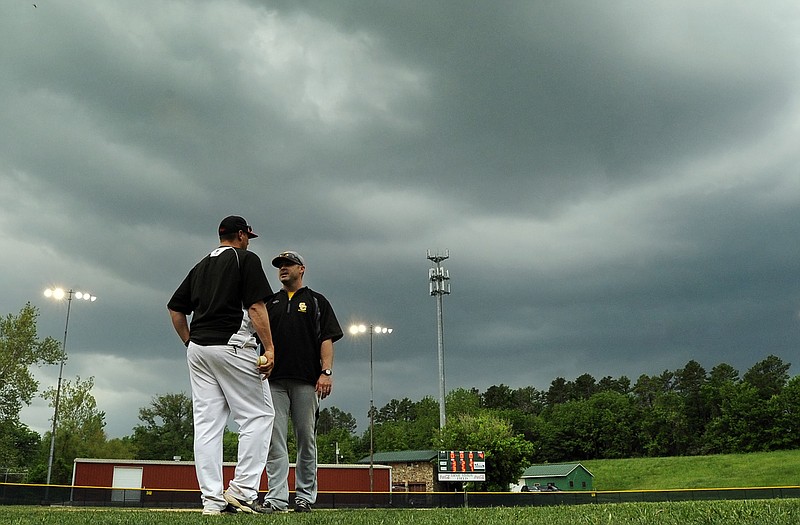 Jefferson City head coach Brian Ash (left) and Sedalia Smith-Cotton head coach Jud Kindle meet on the infield to discuss their options as severe weather moves into the area Monday around Vivion Field.