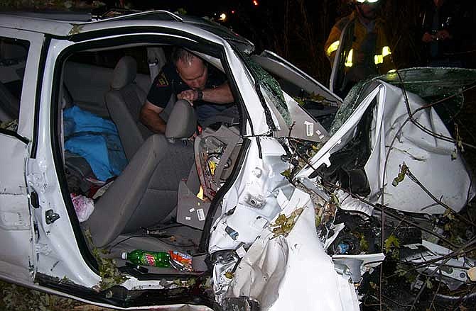 In this Oct. 24, 2006 photo provided by the St. Croix County Sheriff's Office, police investigate the wreckage of a 2005 Chevrolet Cobalt that crashed in St. Croix County, killing Natasha Weigel, 18, and Amy Lynn Rademaker, 15, and injuring the 17-year-old driver, Megan Ungar-Kerns. The vehicle's ignition was found in the "accessory" position and the air bags didn't deploy. General Motors' recent recall of 2.6 million small cars, including the 2005 Cobalt, has shed light on an unsettling fact: Air bags might not always deploy when drivers - and federal regulators - expect them to. 