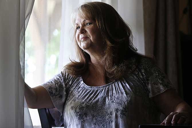In this May 6, 2014 photo, Michelle Pool, who is diabetic and has had a hip replacement, looks out the window of her home in Vista, Calif. The first thing Pool did before picking a health insurance plan under President Barack Obama's health care law was asking her agent to make sure that her longtime primary care doctor was covered. But after her insurance card came in the mail, she learned her doctor wasn't taking her new insurance.