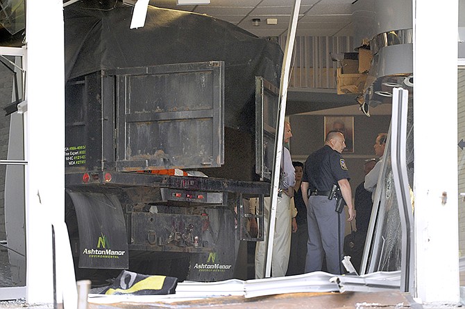 Police and WMAR-TV officials inspect damage caused by a vehicle that crashed into the television station's building on Tuesday in Towson, Md. Officials announced that a man was taken into custody after allegedly crashing the vehicle into the building. 