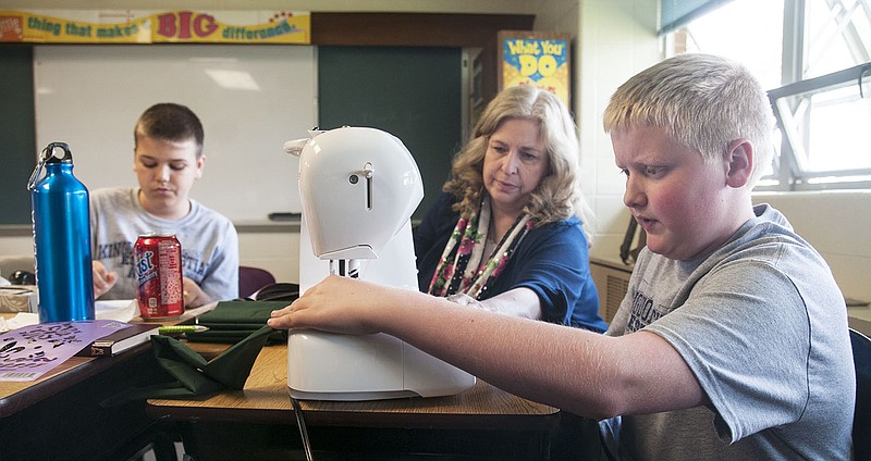 Landon Wright (right), Kingdom Christian Academy fifth-grader sews a cool tie, a garment with special material inside to keep the neck cool, Thursday for soldiers serving in Afghanistan. The fifth grade class donated food, toiletries and other items to soldiers for the Operation Freedom project.