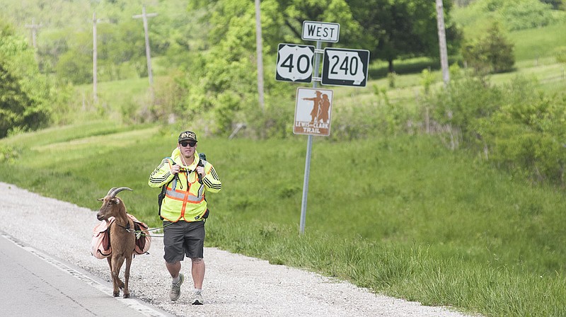 Steve Wescott and his goat, Leroy Brown, head east on Old U.S. Highway 40 outside of Boonville Thursday during their journey from the Space Needle in Seattle to Times Square in New York City. Through his adventure, Wescott hopes to raise money to provide a farm for a orphanage in Nairobi, Kenya.
