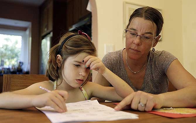 Stacey Jacobson-Francis, right, works on math homework with her 6 year old daughter Luci Wednesday, May 14, 2014, at their home in Berkeley, Calif. As schools around the U.S. implement national Common Core learning standards, parents trying to help their kids with math homework say that adding, subtracting, multiplying and dividing has become as complicated as calculus. Stacey Jacobson-Francis, 41, of Berkeley, California, said her daughter's homework requires her to know four different ways to add. "That is way too much to ask of a first grader. She can't remember them all, and I don't know them all, so we just do the best that we can," she said. 