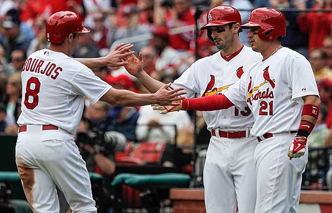 St. Louis Cardinals Matt Carpenter, center, celebrates with Peter Bourjos, left, and Allen Craig, right, after they scored on Michael Wacha's two-run single in the second inning of a baseball game against the Chicago Cubs Thursday, May 15, 2014, in St. Louis.