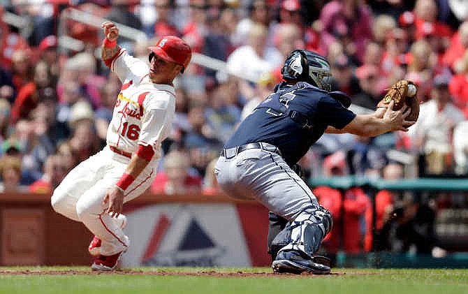 St. Louis Cardinals' Kolten Wong, left, scores as the throw gets past Atlanta Braves catcher Evan Gattis during the fourth inning of a baseball game on Saturday, May 17, 2014, in St. Louis. 