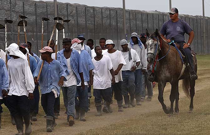 In this Aug. 18, 2011 file photo, a prison guard on horseback watches inmates return from a farm work detail at the Louisiana State Penitentiary in Angola, La. As summer approaches, corrections officials throughout the country must deal with prisoners' potentially fatal exposure to extreme heat. Advocates say rising temperatures are a threat to an increasingly mentally ill and aging prisoner population. Lawsuits over heat conditions in jails and prisons have been filed in Arizona, Wisconsin, Illinois, Louisiana, Georgia and Delaware.