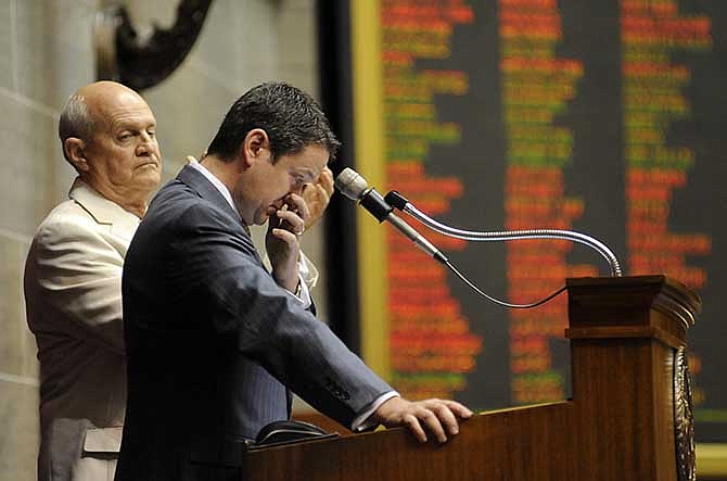 Speaker of the House Timothy Jones wipes his eyes while thanking his family for their support during his time in public service as Dwight Scharnhorst (R-High Ridge), left, and the rest of the Missouri House give Jones a standing ovation at the close of their 2014 session on Friday. Jones, who was first elected to the General Assembly in 2006, will reach the end of his term limit as a state representative before the convening of the 2015 General Assembly.