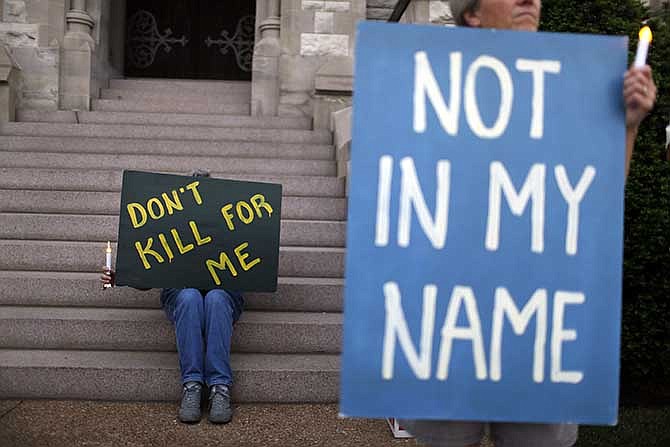 Death penalty opponents Joyce Engle, left, and Kate McCoy hold a signs as they take part in a vigil outside St. Francis Xavier College Church ahead of the scheduled execution of Missouri death row inmate Russell Bucklew on Tuesday, May 20, 2014, in St. Louis. 