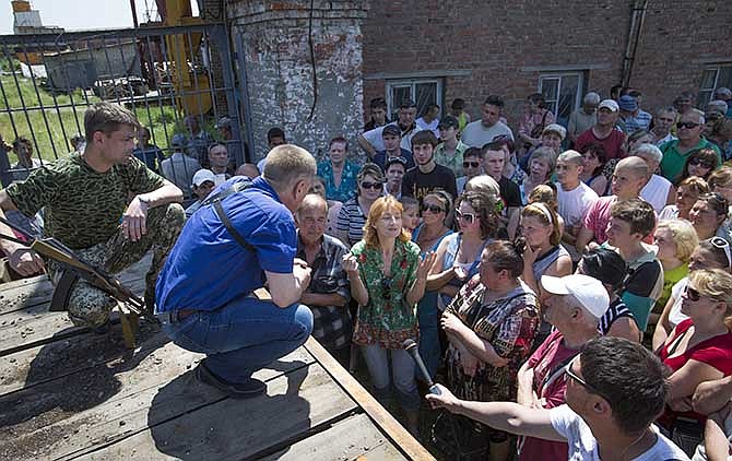 Vyacheslav Ponomarev, center, the self-proclaimed mayor of Slovyansk talks with local citizens whose homes were ruined in a shelling in Slovyansk, eastern Ukraine, Tuesday, May 20, 2014. On Tuesday, the rebels continued to exchange fire with government forces on the outskirts of the eastern city of Slovyansk, which has been the epicenter of clashes. Residents of Slovyansk sounded exasperated and angry with both the warring sides. 