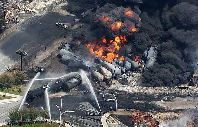 In this July 6, 2013 photo, smoke rises from flaming railway cars that were carrying crude oil after it a train derailed in downtown Lac Megantic, Quebec, Canada. A large swath of the town was destroyed after the derailment, sparking several explosions and fires that claimed 47 lives.