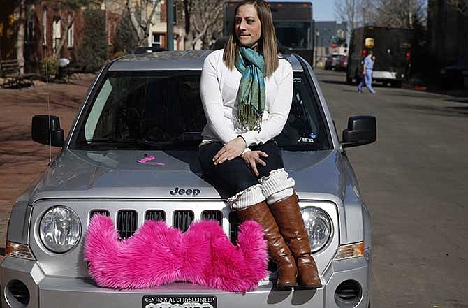  In this Feb. 28, 2014 file photo, part time Lyft driver Brittany Cameron sits on the hood of her own vehicle, which she uses to give rides, and which is adorned with Lyft's trademark pink mustache, in downtown Denver. 