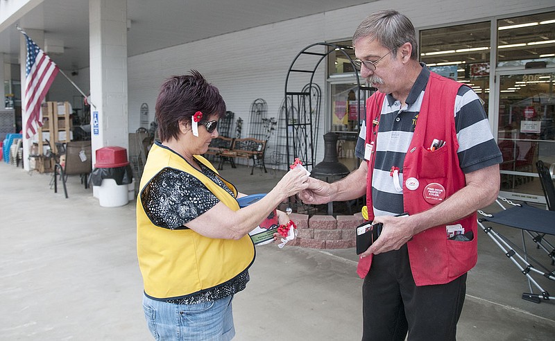 Kevin Flynn, Westlake Ace Hardware employee, buys a buddy poppy Saturday from Fulton VFW Post volunteer Peggy Houchins. Flynn said he bought the buddy poppy in honor of his son, who will return to the U.S. from Afghanistan this week.