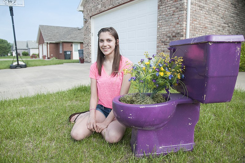 
Alyssa Hauck poses for a photo Thursday next to a purple toilet in her front yard. Hauck's Relay for Life Team, the Tumor-nators, started the fundraiser, "purple potty project," two weeks ago and have raised about $500.