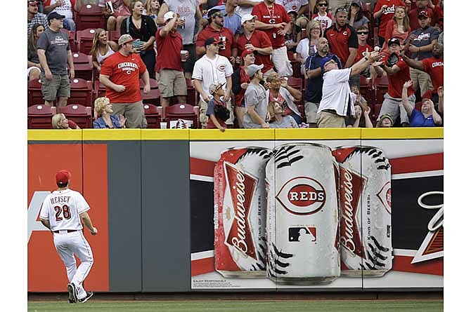 Cincinnati Reds center fielder Chris Heisey watches as a fan catches a home run hit by St. Louis Cardinals' Yadier Molina in the fourth inning of a baseball game, Saturday, May 24, 2014, in Cincinnati. 