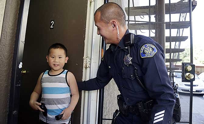 In this May 21, 2014 photo, San Jose police officer Huan Nguyen, right, visits with Steven Lam in San Jose, Calif. Nguyen came to the aid Lam and his family after his father Phuoc Lam was killed during a road rage incident. Just two weeks since the murder, close to $100,000 in aid has poured in, from the local Vietnamese community and far beyond, including Houston, Boston, New York, even London. 