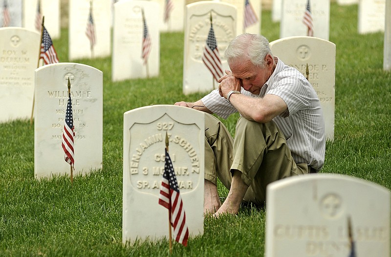 Gene Wilson of Jefferson City wipes his eyes as he sits among the marble headstones while listening to retired Maj. Gen. Henry Stratman speak of the costs of war during Monday's Memorial Day program at the Jefferson City National Cemetery.