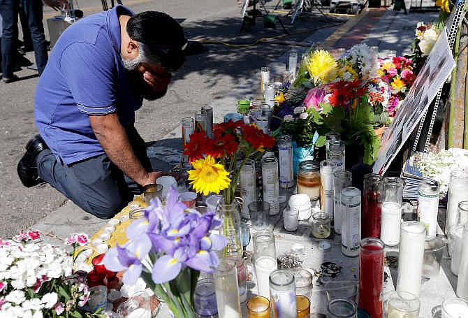 Jose Cardoso pays his respects at a makeshift memorial in front of the IV Deli Mart, where part of Friday night's mass shooting took place by a drive-by shooter Sunday, May 25, 2014, in the Isla Vista area near Goleta, Calif. Sheriff's officials said Elliot Rodger, 22, went on a rampage near the University of California, Santa Barbara, stabbing three people to death at his apartment before shooting and killing three more in a crime spree through a nearby neighborhood.