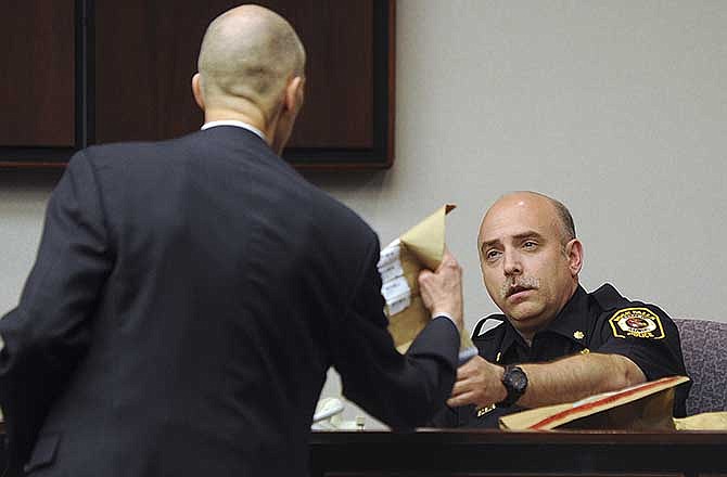 Prosecutor Steve Nate hands bags of evidence to Commander Doug Coppotelli of the Rock Falls Police Department during the murder trial of Nicholas Sheley in Rock Island, Ill., on Wednesday, May 21, 2014. Sheley is on trial for the June 2008 deaths of Brock Branson, 29, Kilynna Blake, 20, her 2-year-old son, Dayan, and Kenneth Ulve, 25, in Rock Falls.