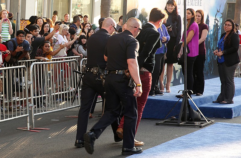 A fan is walked off carpet in handcuffs after allegedly attacking Brad Pitt at the world premiere of "Maleficent" at the El Capitan Theatre on Wednesday in Los Angeles. 