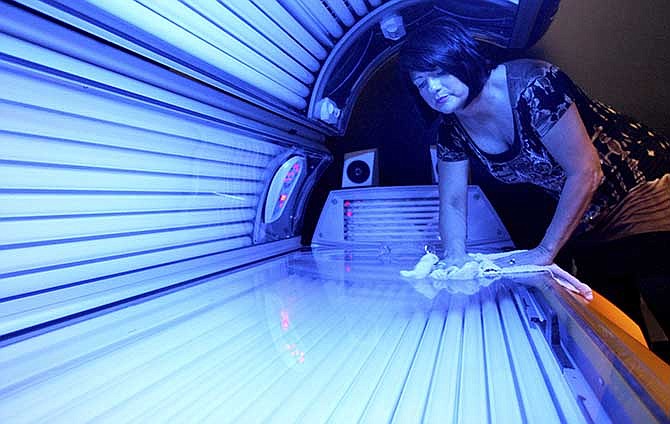 In this April 2, 2014 file photo, Teresa Lynch, owner of Dynamic Tanning in DeKalb, Ill., wipes down a tanning bed. 