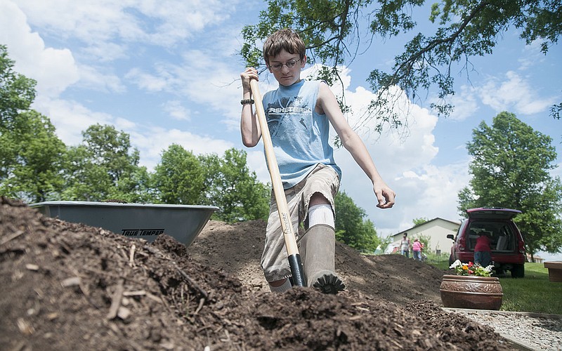 Tanner Bowser, 13, digs compost for SERVE, Inc.'s garden Thursday. Bowser said he enjoys volunteering at the garden because he likes helping others and getting dirty.