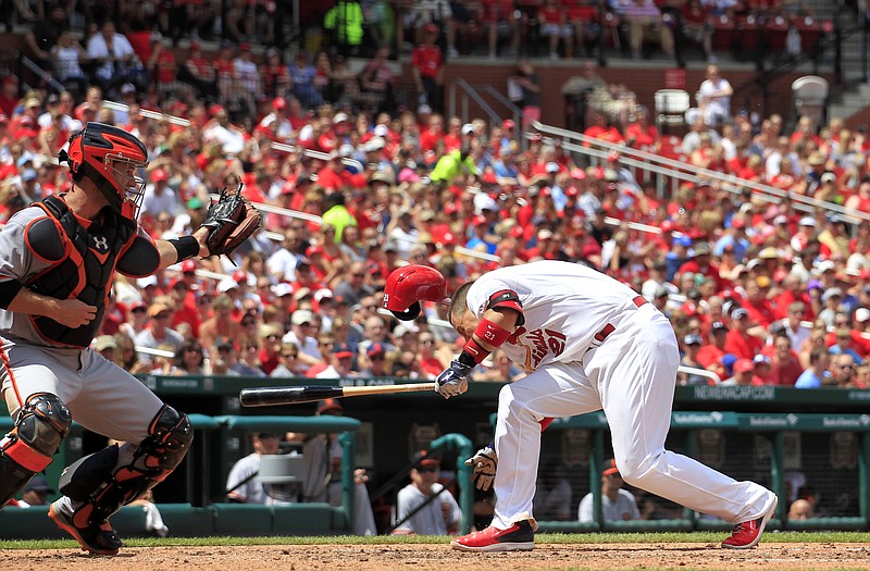 Allen Craig of the Cardinals recoils after being hit in the head by a pitch from the Giants' 
Tim Hudson in the third inning of Sunday's game in St. Louis. Looking on is San Francisco catcher Buster Posey. Craig stayed in the game.