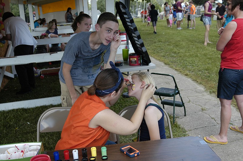 At the face-painting booth at the annual Annunciation Picnic staffed by Jack Johnston and Rachael Hoback, Makenna Belt gets the "treatment" provided by Hoback.