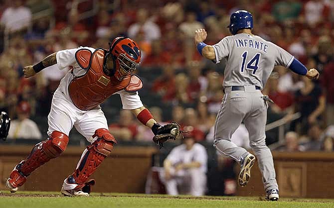 Kansas City Royals' Omar Infante, right, scores as he avoids the tag from St. Louis Cardinals catcher Yadier Molina during the ninth inning of a baseball game Tuesday, June 3, 2014, in St. Louis. 