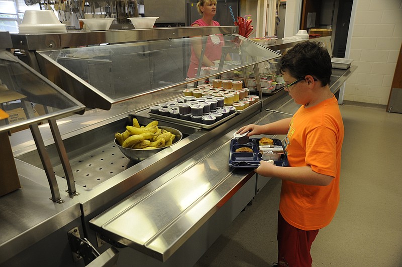 Fourth-grader Zachary Schrader picks up his sausage and biscuit, cereal, juice and banana from the breakfast line Tuesday at Russellville Elementary School.