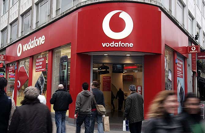 In this Tuesday, Feb. 24, 2009 file photo, people walk by a Vodafone branch in central London. Vodafone, one of the world's largest cellphone companies, on Friday, June 6, 2014 revealed the scope of government snooping into phone networks, saying authorities in some countries are able to directly access an operator's network without seeking permission.