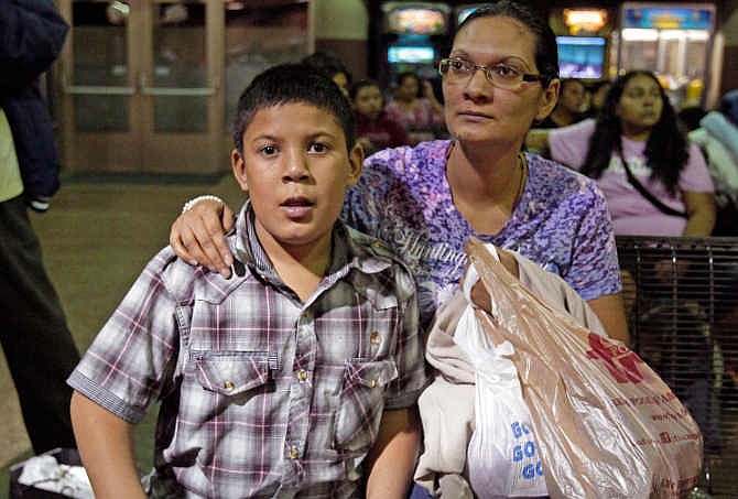  In this May 29, 2014 file photo, Maria Eva Casco, left, and her son Christian Casco of El Salvador, sit at at the Greyhound bus terminal, Thursday, May 29, 2014 in Phoenix. Central American families arrested in Texas will continue to be flown to Arizona, and hundreds of unaccompanied minors a day are being shipped to a federal detention center in the southern part of the state, Gov. Jan Brewer's spokesman says. 