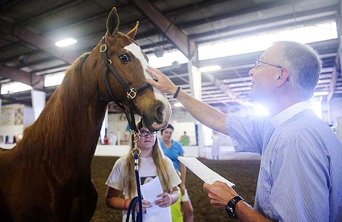 In this photo taken on May 31, 2014, from left, Lily Callahan, 12, watches as her horse Bob is blessed by Rev. H. Knute Jacobson, right, during an animal blessing at the 21st annual Calvary Episcopal Charity Horse Show at the Central Missouri Events Center in Columbia, Mo. (AP Photo/The Columbia Daily Tribune, Nick Schnelle)