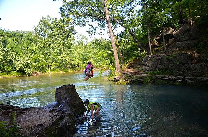 Annabel Butler jumps into to one of the numerous natural spring along the course of the North Fork of the White River, while Bailee Butler scampers from the cold water.