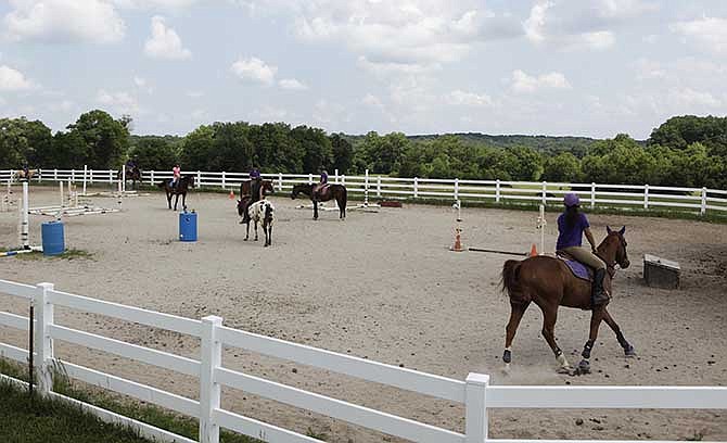 The advanced riding team practice on transitions, or a change in gait or speed of gait, and gymnastic jumps
last week at the Wild Horse Creek Ranch and Riding Academy. The advanced riding team ride everyday under the
instruction of Anne Thill. In order to be on that team, "they have to be able to be in total control of the horse, and
themselves," Anne said.