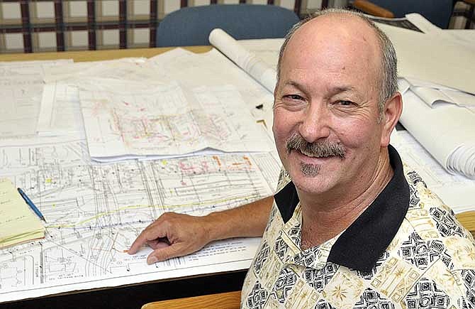 MoDOT's Joe Bax is seated at a table of maps of projects on which he or other surveyors have gathered the information.