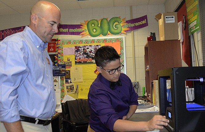 Teacher Garth Haugen, left shows Kord Pearson how to operate a 3-D printer, which has become an fascinating new tool for students and teachers at Lewis and Clark Middle School. Although the device arrived at the end of the school year, Haugen already has incorporated the machine into his lesson planning to help his student better understand the engineering design process.