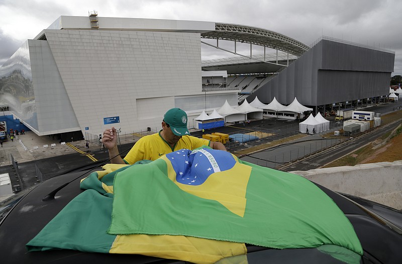 A Brazilian fan tries to tie his country's flag on top of his car outside Arena de Sao Paulo on Tuesday in Sao Paulo, Brazil. The World Cup opens Thursday with the host country taking on Croatia.