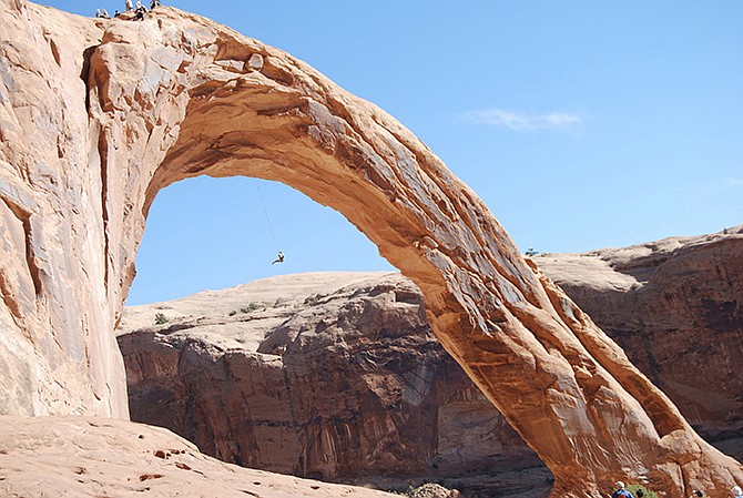 A person swings on the Corona Arch near Moab, Utah. Federal officials are considering outlawing the stunt made so popular on YouTube that state authorities banned from commercial outfitters in 2013. 