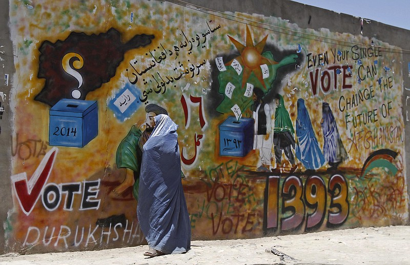 An Afghan woman walks past a mural to support voting in Kandahar, south of Kabul, Afghanistan, Friday. With fears of violence high, Afghanistan braced for a final election on Saturday to choose a new president to replace the only leader the nation has known since the Taliban were ousted.